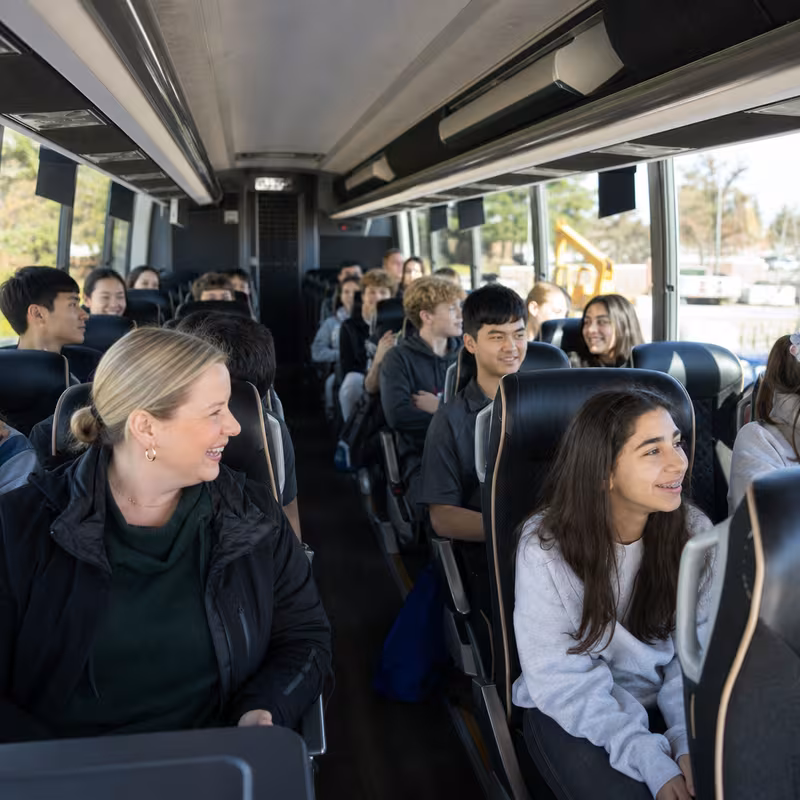 Group boarding a white charter bus for School Transportation transportation in Jacksonville